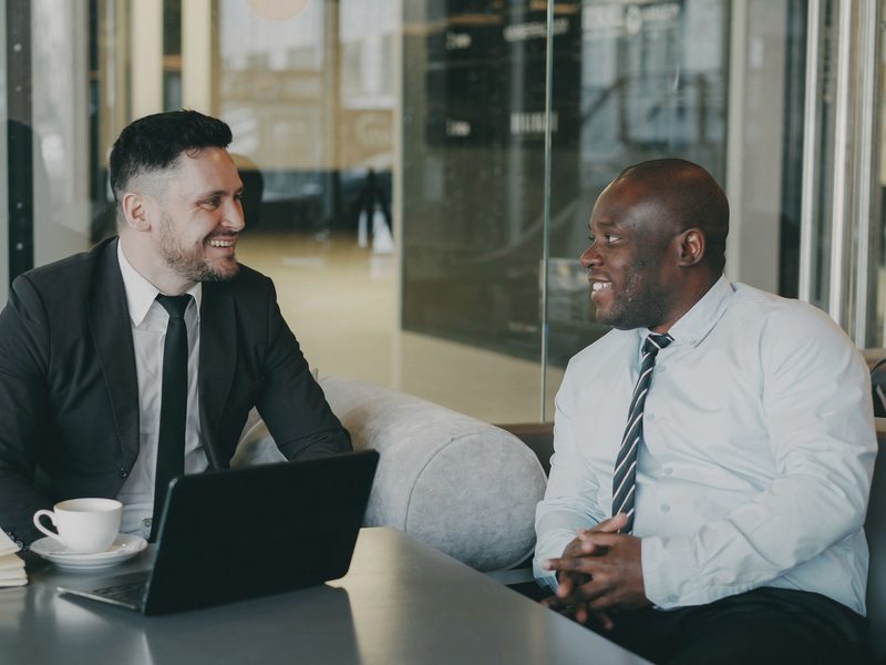 Two colleagues in a one-to-one conversation in a glass-walled meeting room